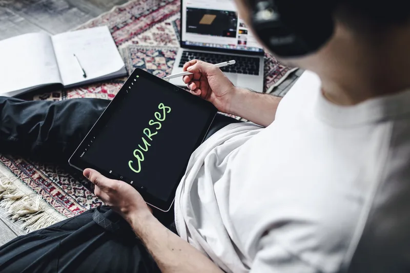 Person studying online courses on a tablet with headphones, engaged with digital learning content